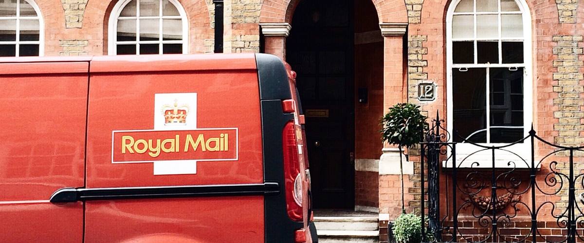 A red royal mail van delivering a parcel